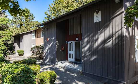 the front of a building with a driveway and a white door at Whisperwood, Seattle, WA