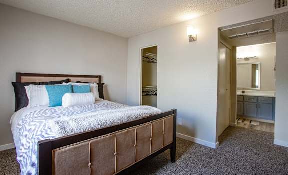 a bedroom with a bed and a bathroom with a mirror