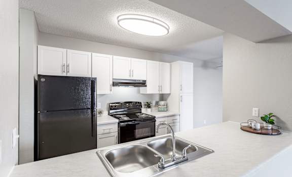 a kitchen with white cabinets and black appliances