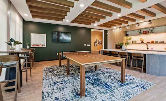 A room with a wooden table and chairs and a blue rug.