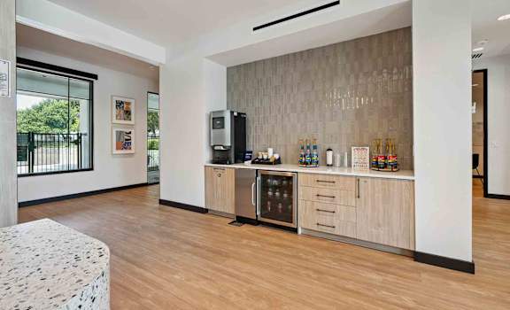 A kitchen area with a refrigerator, microwave, and a counter with bottles and glasses on it.