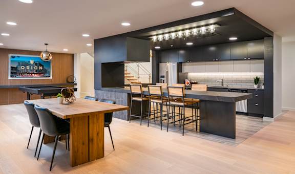 the kitchen and dining area of a modern home with a wood floor and black cabinets