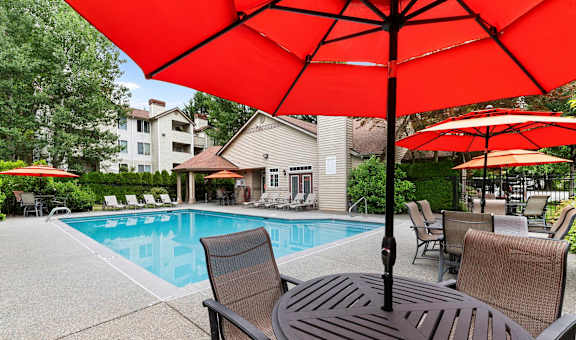A red umbrella is over a table with chairs around it.