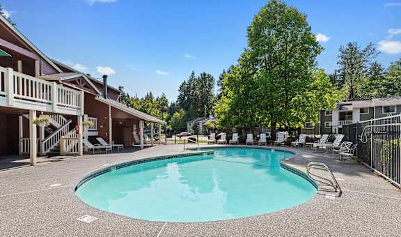 A large outdoor swimming pool surrounded by a fence and trees.