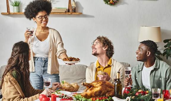 a group of people are sitting around a thanksgiving dinner table