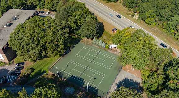 A tennis court surrounded by trees and buildings.