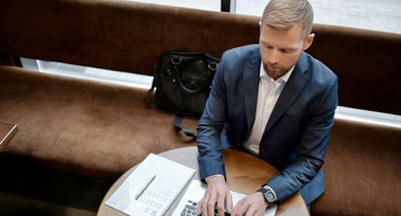 A man in a suit is typing on a laptop.