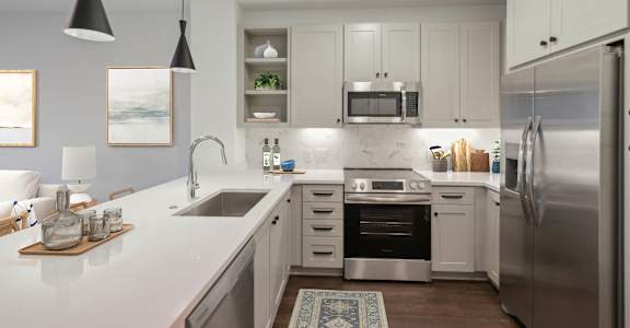 A modern kitchen with white cabinets and stainless steel appliances. at The Sully, Chantilly, Virginia