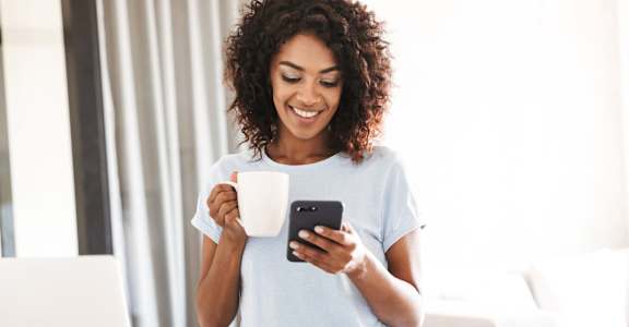 a woman looking at her phone while holding a cup of coffee
