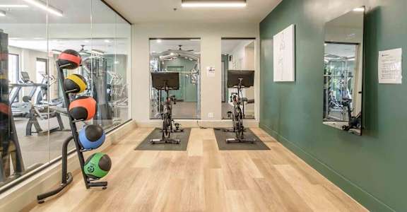 A gym with a variety of equipment including a stationary bike and a rowing machine.