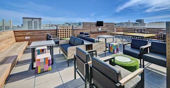 a roof top patio with tables and chairs and a view of the city at L Seven, CA 94103