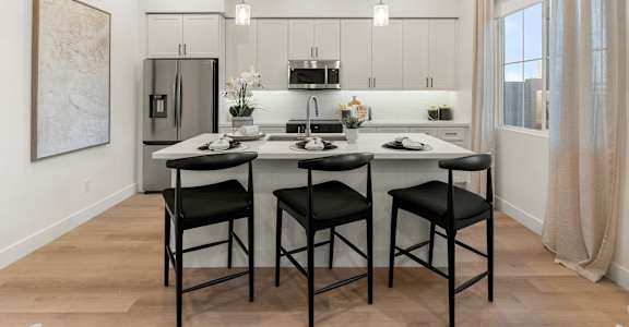 A modern kitchen with a dining table and chairs.