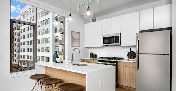 A modern kitchen with a white countertop and stainless steel appliances.