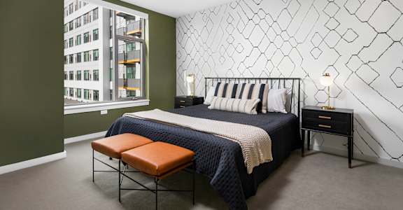 A bedroom with a bed, bench, and wall decoration.