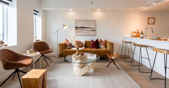 A modern living room with a yellow sofa and a glass coffee table.