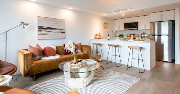 A modern living room with a sofa, coffee table, and kitchen area.