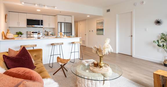 A modern living room with a glass coffee table and a bar area.