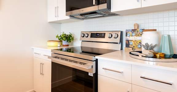 A modern kitchen with white cabinets and a black microwave above the stove.