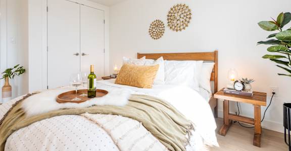 A cozy bedroom with a large bed and a tray of food on it.