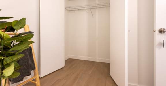 A white closet with a wooden floor and a door on the right.