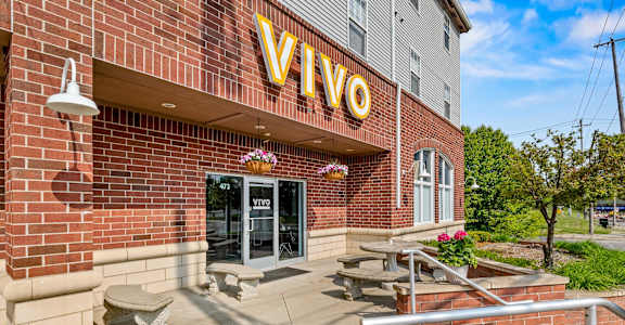 VIVO sign on a brick building with a bench in front.