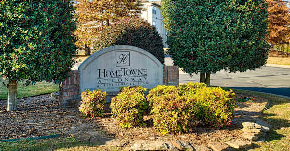 A sign that says Home Town in front of some trees.