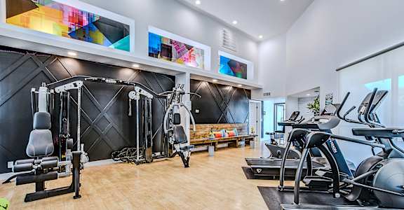A gym with a variety of equipment including treadmills, weights, and exercise machines.