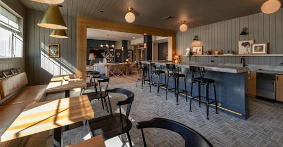 A modern kitchen and dining area with a bar and stools.
