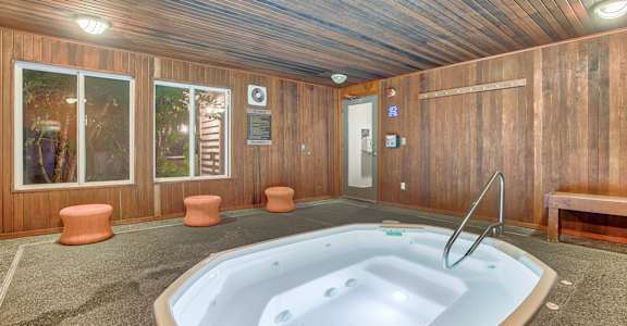 A hot tub is in the middle of a room with wood paneling.
