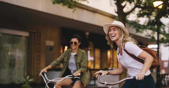 two women riding bikes down the street