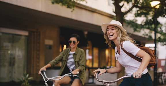 two women riding bikes down the street