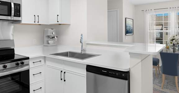 A modern kitchen with white cabinets and appliances. at Reflection Pointe, Flowood, MS