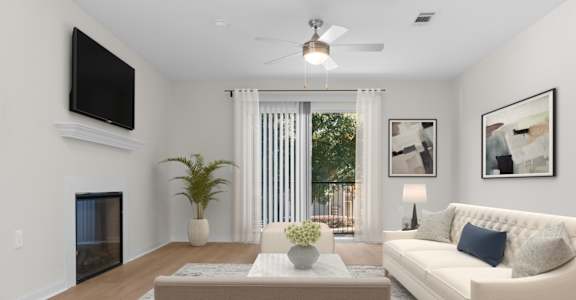 A living room with a white couch, a coffee table, a flat screen TV, and a ceiling fan. at Reflection Pointe, Flowood, MS