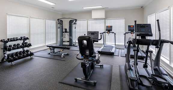 A well-lit gym with treadmills, weights, and exercise equipment.