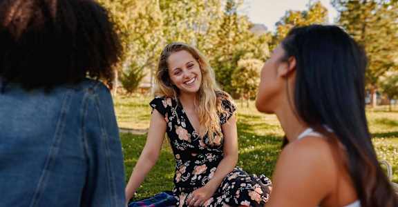 Three women having a picnic in a park.