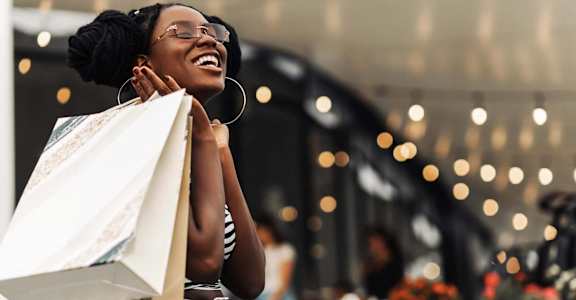 A woman is holding a shopping bag and smiling.