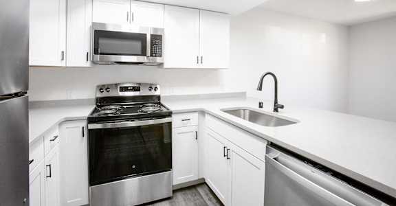 a kitchen with white cabinets and stainless steel appliances