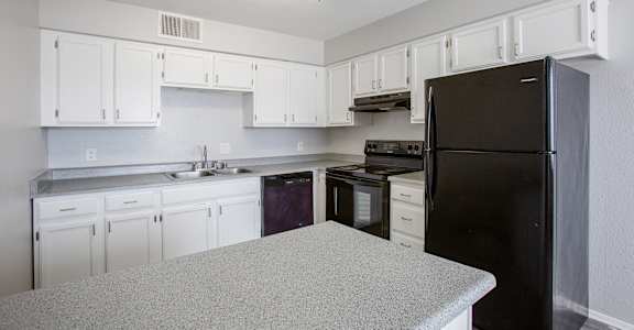 an empty kitchen with white cabinets and black appliances