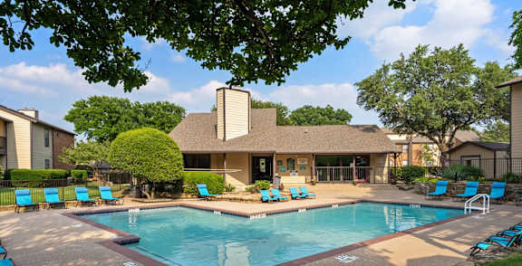 A pool surrounded by palm trees and a building.