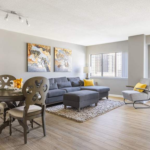 A living room with a grey couch, a black table and a painting on the wall.