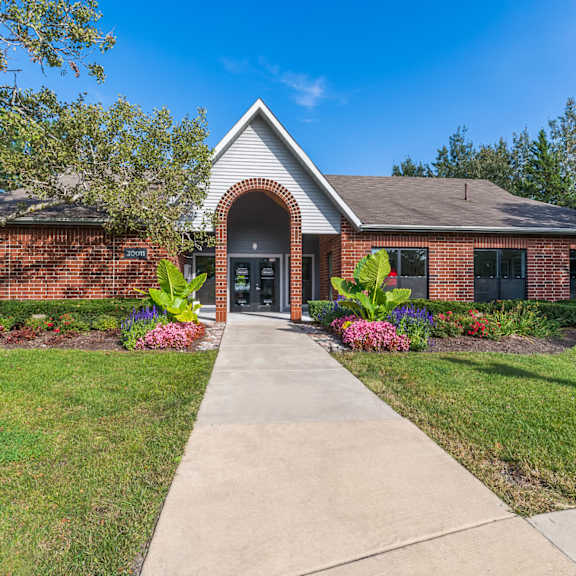 A brick house with a large front yard and a concrete walkway leading to the front door.