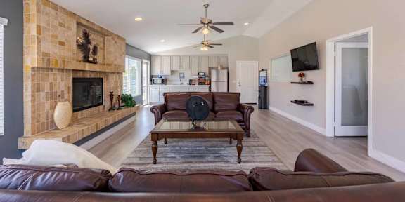 A living room with a brown leather couch and a fireplace.