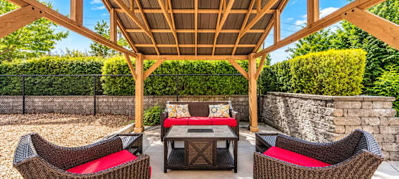 A wooden pergola with a table and chairs underneath it.
