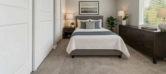 A bedroom with a bed, nightstands, and a window with blinds.
