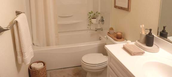 A white bathroom with a towel hanging on the towel rack.