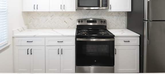 A kitchen with white cabinets and a black stove top oven.