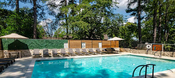 A large outdoor swimming pool surrounded by trees.