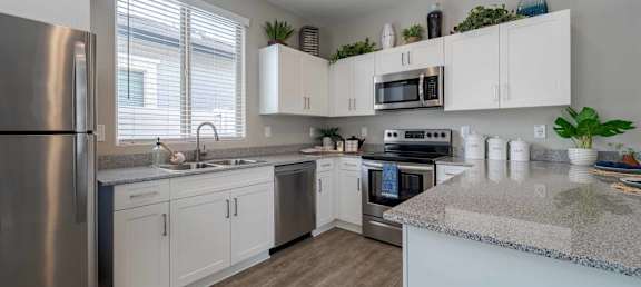 A kitchen with white cabinets and a granite countertop.