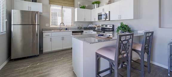 A kitchen with a refrigerator, microwave, and sink.
