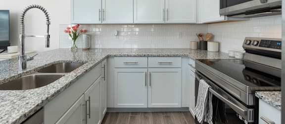 A kitchen with white cabinets and a black microwave.